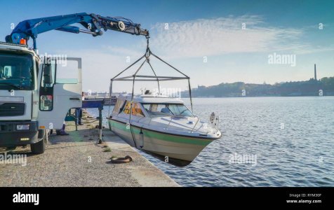 a-crane-lifting-up-a-speedboat-from-the-port-in-stockholm-sweden-with-the-truck-crane-on-the-s...jpg